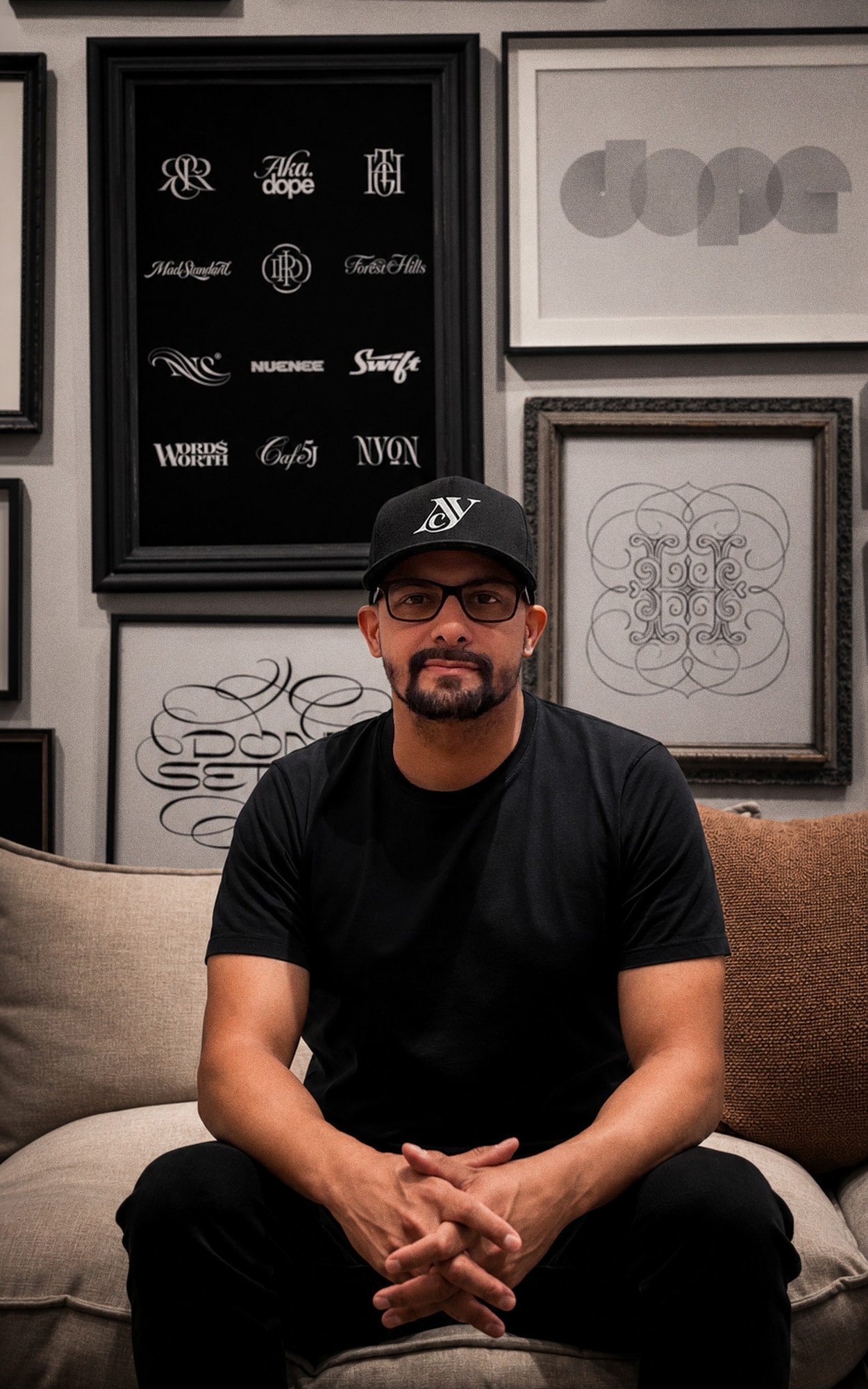 David Soto seated in front of a wall of his lettering and logo work